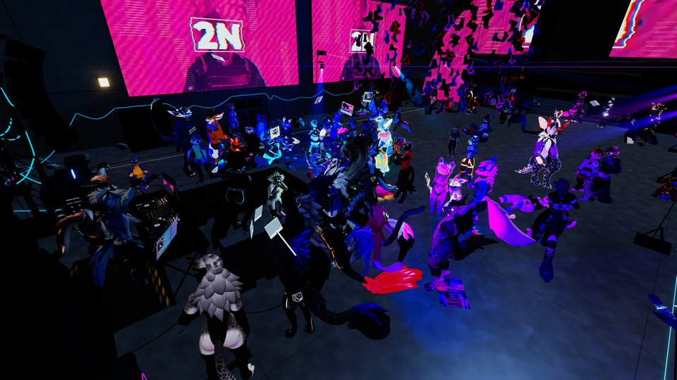 A view across the crowd beneath pink stage screens and coloured lights.